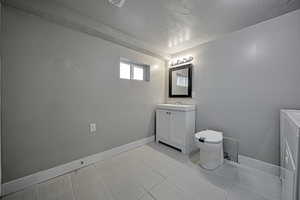 Bathroom featuring vanity, a textured ceiling, and washer / clothes dryer