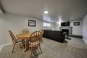 Dining space featuring a tile fireplace, a textured ceiling, and light carpet