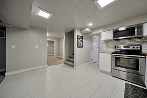 Kitchen with white cabinets, stainless steel appliances, a textured ceiling, butcher block counters, and light tile patterned flooring
