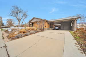 View of side of property featuring concrete driveway and an attached carport