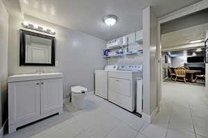 Laundry area with a textured ceiling, washing machine and dryer, and light tile patterned floors