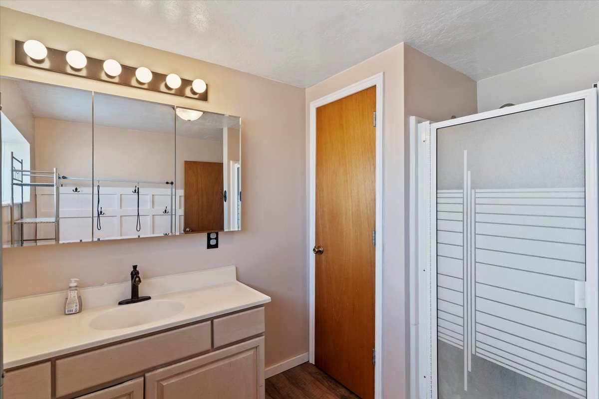 Bathroom with vanity, a shower stall, and dark wood finished floors