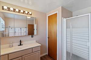 Bathroom with vanity, a shower stall, and dark wood finished floors