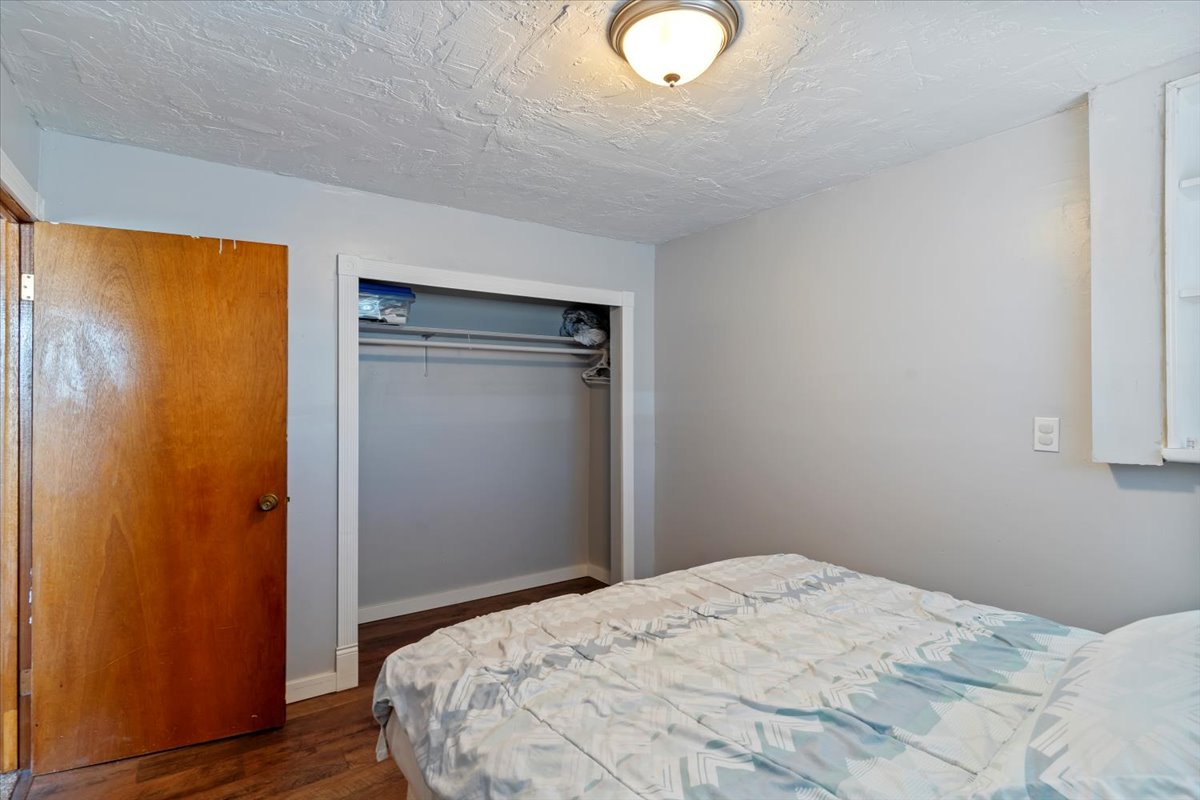 Bedroom with dark wood finished floors, a closet, and a textured ceiling