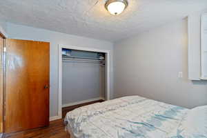 Bedroom with dark wood finished floors, a closet, and a textured ceiling