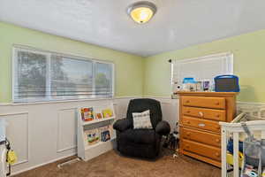 Bedroom with a decorative wall, a wainscoted wall, and carpet flooring