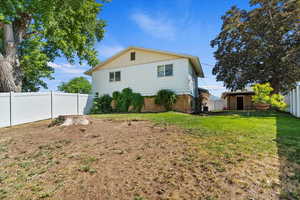 Back of house with a fenced backyard, brick siding, and a storage unit