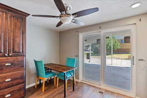 Dining area with light wood-type flooring, a textured ceiling, and a ceiling fan