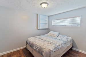 Bedroom with dark wood finished floors and a textured ceiling