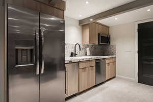 Kitchen with stainless steel appliances, light stone countertops, backsplash, modern cabinets, and recessed lighting