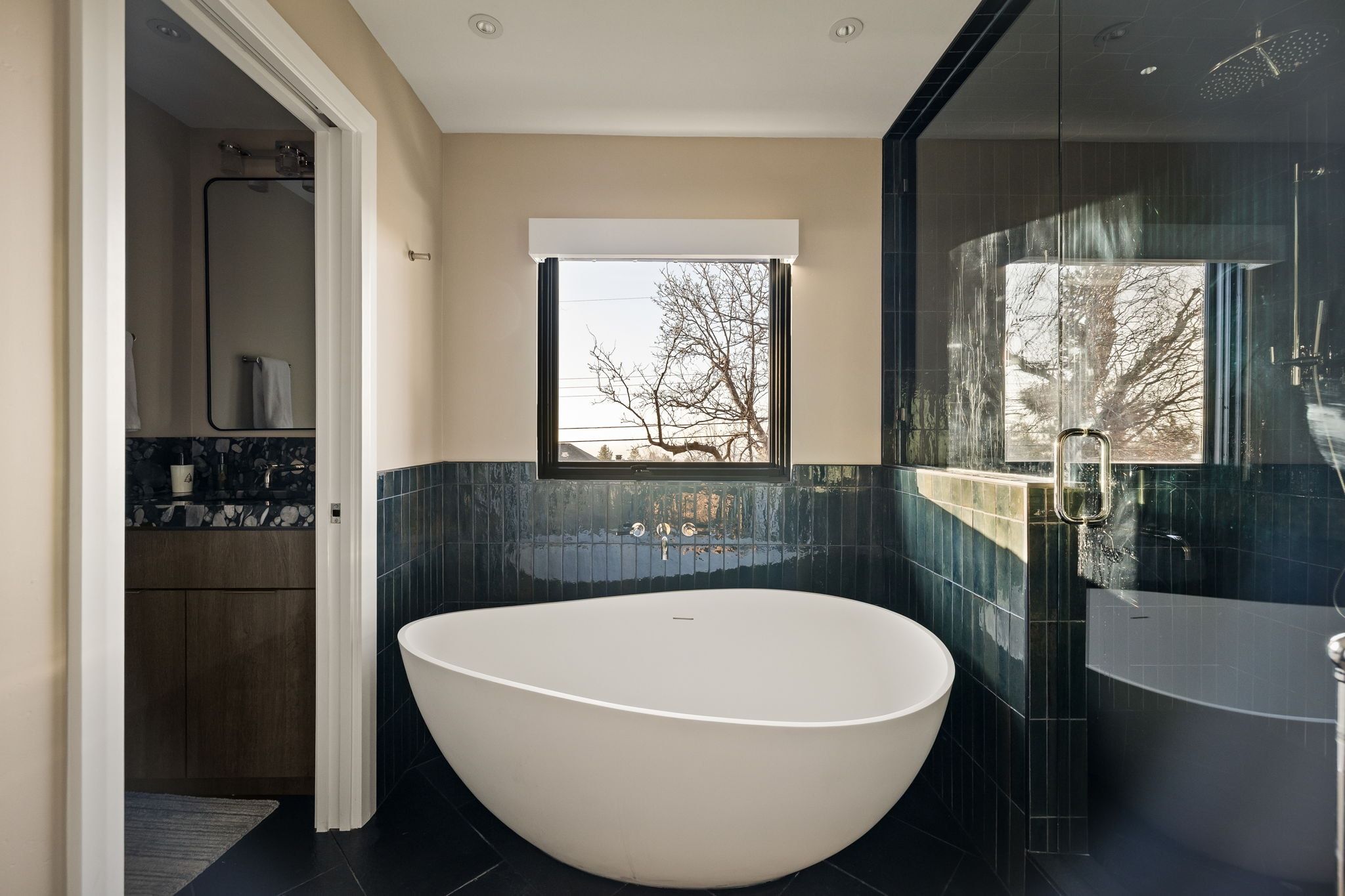 Full bathroom featuring a freestanding tub, vanity, tile walls, and a wainscoted wall