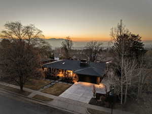 View of front of home featuring concrete driveway, a garage, roof with shingles, and a chimney