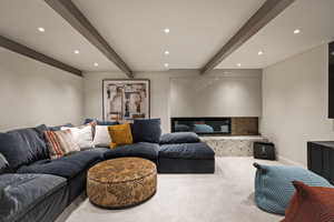 Living area featuring carpet floors, recessed lighting, beamed ceiling, and a stone fireplace