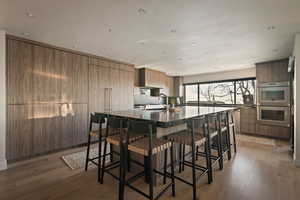 Kitchen featuring a breakfast bar, stainless steel double oven, modern cabinets, recessed lighting, and light wood finished floors