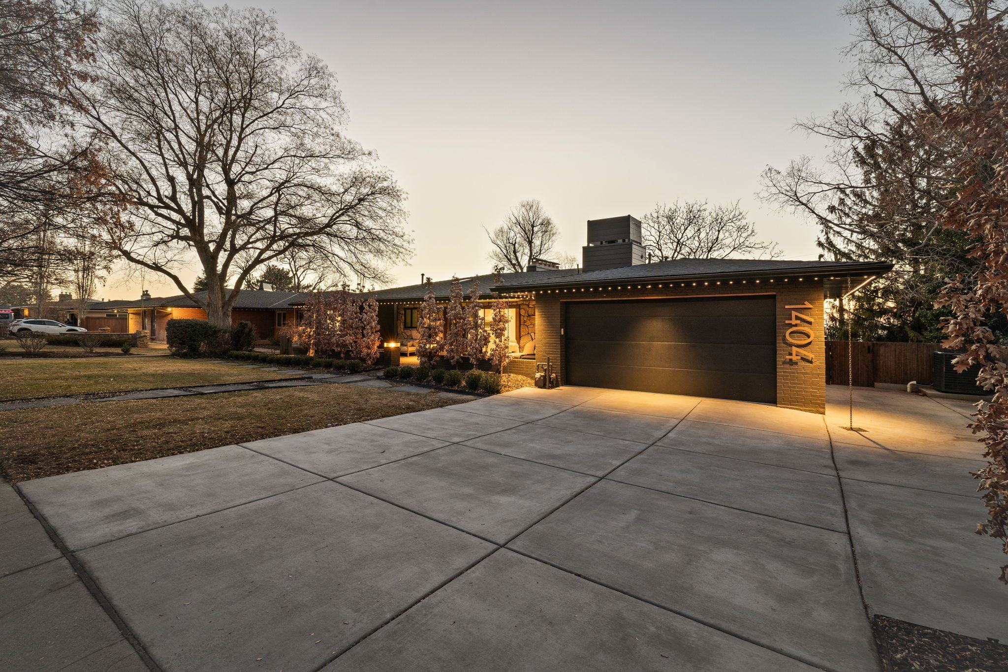 View of front of property with a chimney, concrete driveway, an attached garage, brick siding, and a lawn