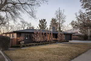 View of front of house featuring a chimney, a garage, and concrete driveway