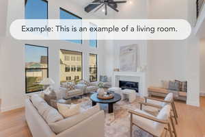 Living area with light wood finished floors, a glass covered fireplace, a high ceiling, ceiling fan, and healthy amount of natural light