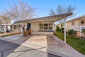 View of front of property with a front yard, a carport, and a patio area