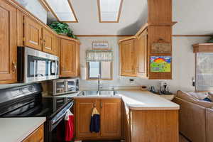 Kitchen with black / electric stove, wallpapered walls, light countertops, open floor plan, and stainless steel microwave