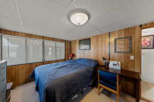 Bedroom featuring wooden walls and a paneled ceiling
