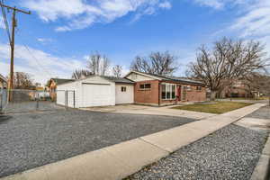 Ranch-style house with concrete driveway, brick siding, a gate, and roof with shingles