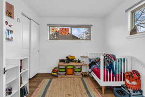Bedroom featuring wood finished floors, a closet, and a crib