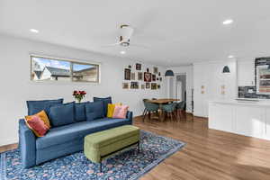 Living room with light wood-style flooring, ceiling fan, and recessed lighting