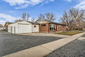 Ranch-style house with concrete driveway, brick siding, roof mounted solar panels, roof with shingles, and a garage