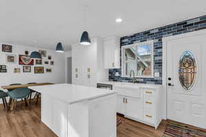 Kitchen featuring white cabinets, pendant lighting, dark wood finished floors, and light stone counters