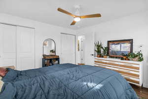 Bedroom featuring two closets, ceiling fan, and dark wood-style floors