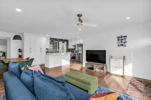 Living area with light wood-style floors, ceiling fan, and recessed lighting