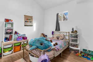 Bedroom with wood finished floors and lofted ceiling