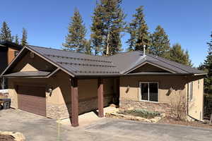 View of front facade featuring stone siding, stucco siding, and a metal roof