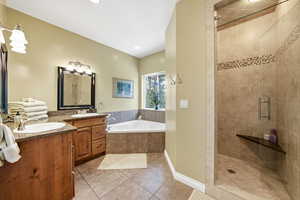 Bathroom with two vanities, a shower stall, light tile patterned floors, and a garden tub