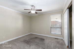 Carpeted empty room with crown molding and a ceiling fan