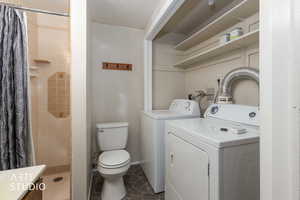 Full bathroom with a textured ceiling, a shower stall, vanity, and separate washer and dryer