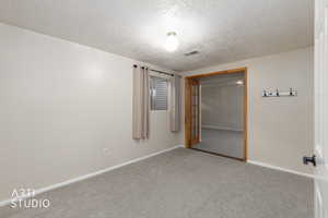 Unfurnished bedroom with a closet, a textured ceiling, and carpet floors