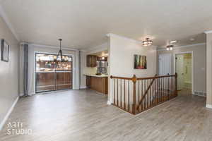 Unfurnished room with light wood-style floors, crown molding, and a textured ceiling
