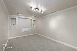 Carpeted spare room featuring a textured ceiling and ornamental molding