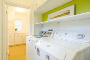 Laundry area featuring light wood-type flooring and separate washer and dryer
