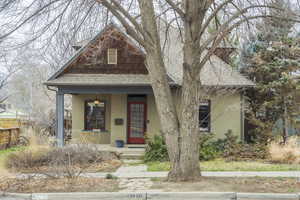 View of front facade with roof with shingles, a porch, and brick siding