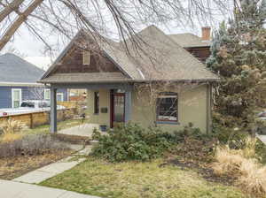 Bungalow featuring a porch, a chimney, roof with shingles, and brick siding