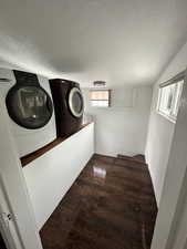 Laundry room with dark wood-style floors, a textured ceiling, and independent washer and dryer
