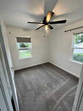 Unfurnished room featuring dark colored carpet and ceiling fan