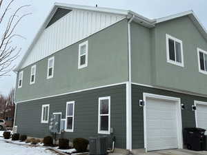 View of side of property featuring a garage, stucco siding, and board and batten siding