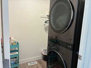 Laundry area featuring light wood finished floors and stacked washer / drying machine