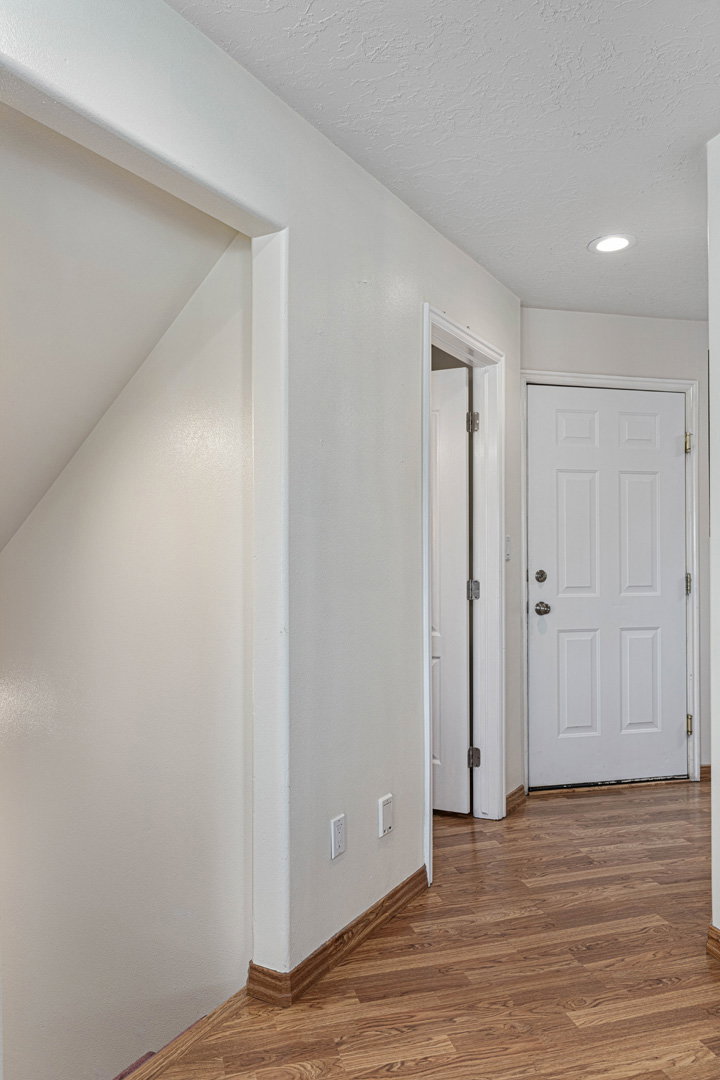 Hallway off the family/tv and dining nook area that leads to downstairs (first left), powder bathroom (second left), garage (third left), and laundry room (follow hall to right).