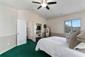 Primary bedroom looking from the bathroom towards the entrance. There is a built-in tv/entertainment area to the right of the door leading out.