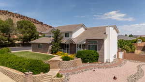 View of front of house featuring brick siding, a tile roof, a mountain view, and a chimney