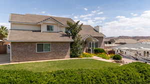 View of front facade featuring brick siding, a chimney, and a tiled roof